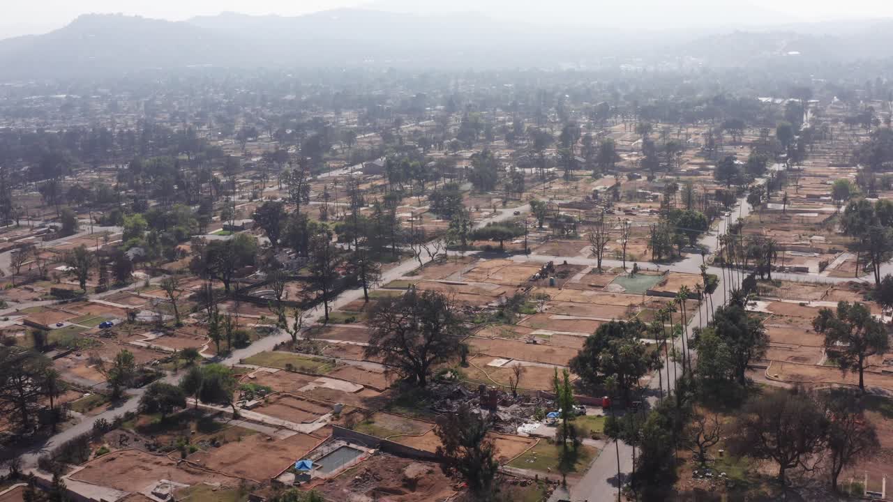 Aerial descending and panning shot of cleared residential lots burned by the Eaton Fire in Altadena, California. 4K