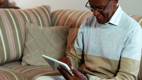 senior man using digital tablet in living room