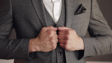 buttoning jacket with hands close up, man in suit fastens buttons on his jacket preparing to go out