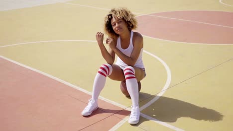 attractive female athlete sits on basketball