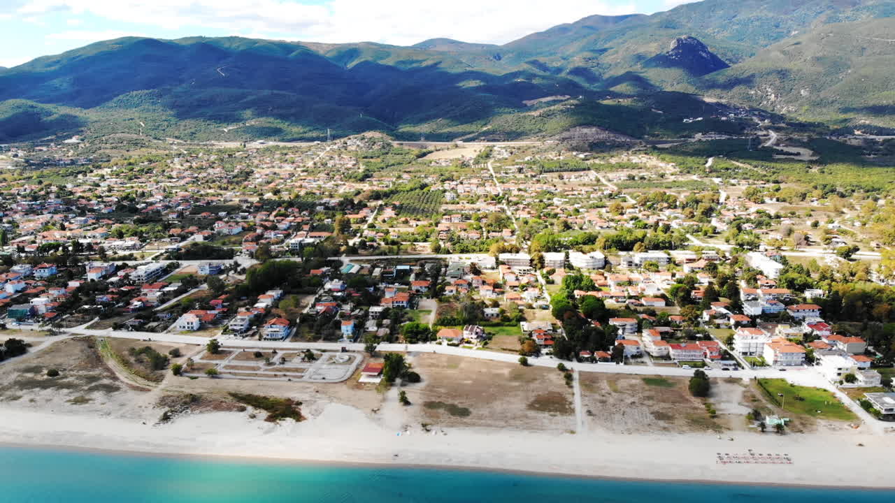 Asprovalta with multiple buildings and greenery, green hills on the background. Aegean sea coast. Sunny day. Greece