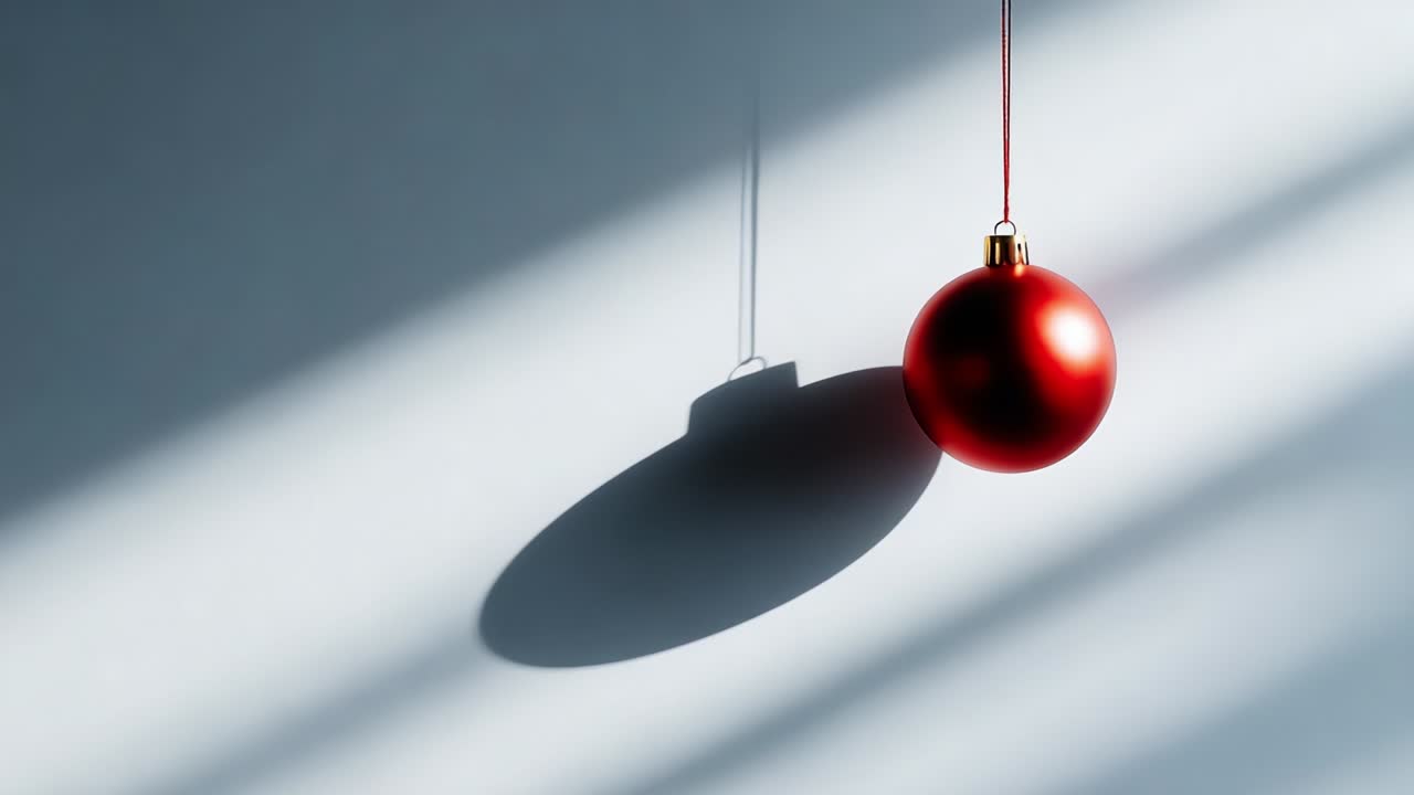 A Bright Red Ornament Suspended Against a Soft Gray Background, Casting Intriguing Shadows and Highlighting the Subtle Contrast Created by the Light and Darkness in the Composition