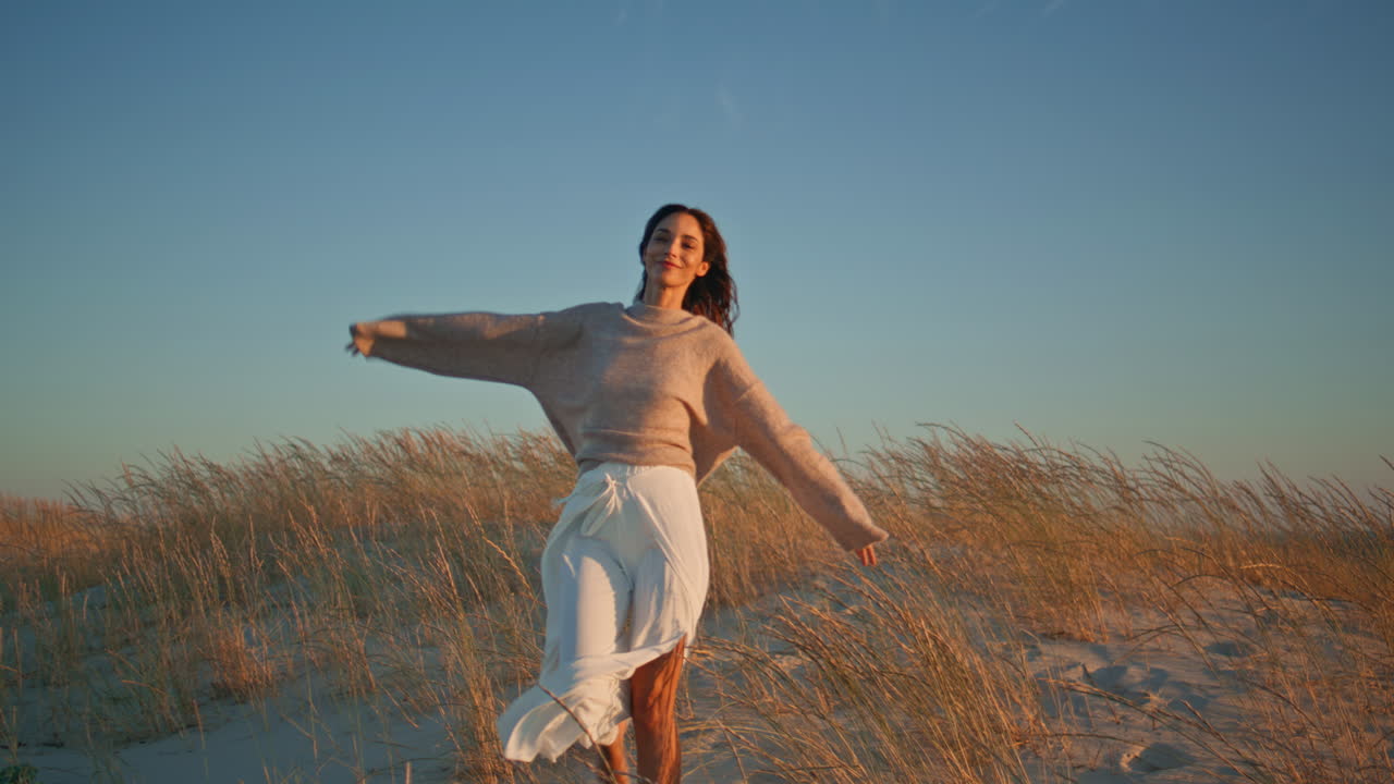 Lady walking dry grass enjoying evening wind. Smiling model strolling grassland