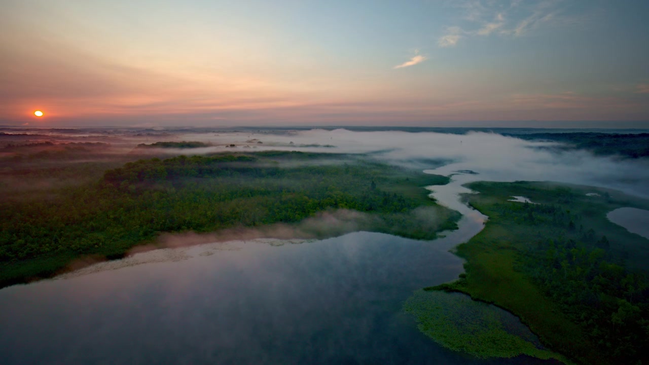 A drone soars above the fog-covered Huron River near Milford, Michigan, at daybreak.