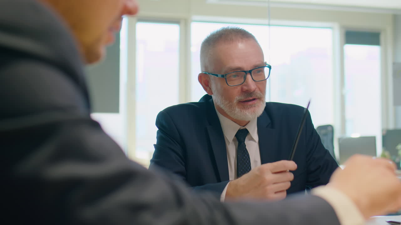 Senior Businessman Talking to Colleagues at Office Meeting