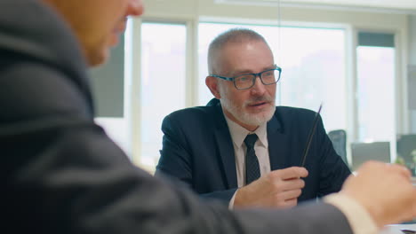 senior businessman talking to colleagues at office meeting