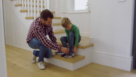 father tying his sons shoelaces in a comfortable home 4k