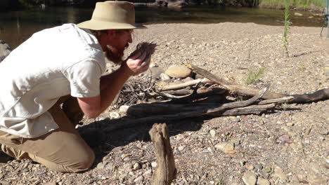 Australian-bush-man-starts-fire-by-blowing-into-a-tinder-bundle-in-the-bush