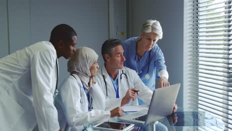 front view of multi-ethnic doctors discussing over laptop in hospital