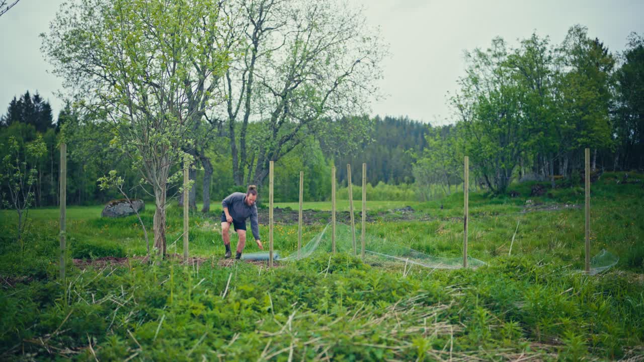 Man Building Fence Using Metal Wire Mesh - Wide Shot