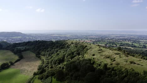 AERIAL---Beautiful-hills-and-a-blue-sky-near-Uley,-Cotswolds,-England,-reverse-shot