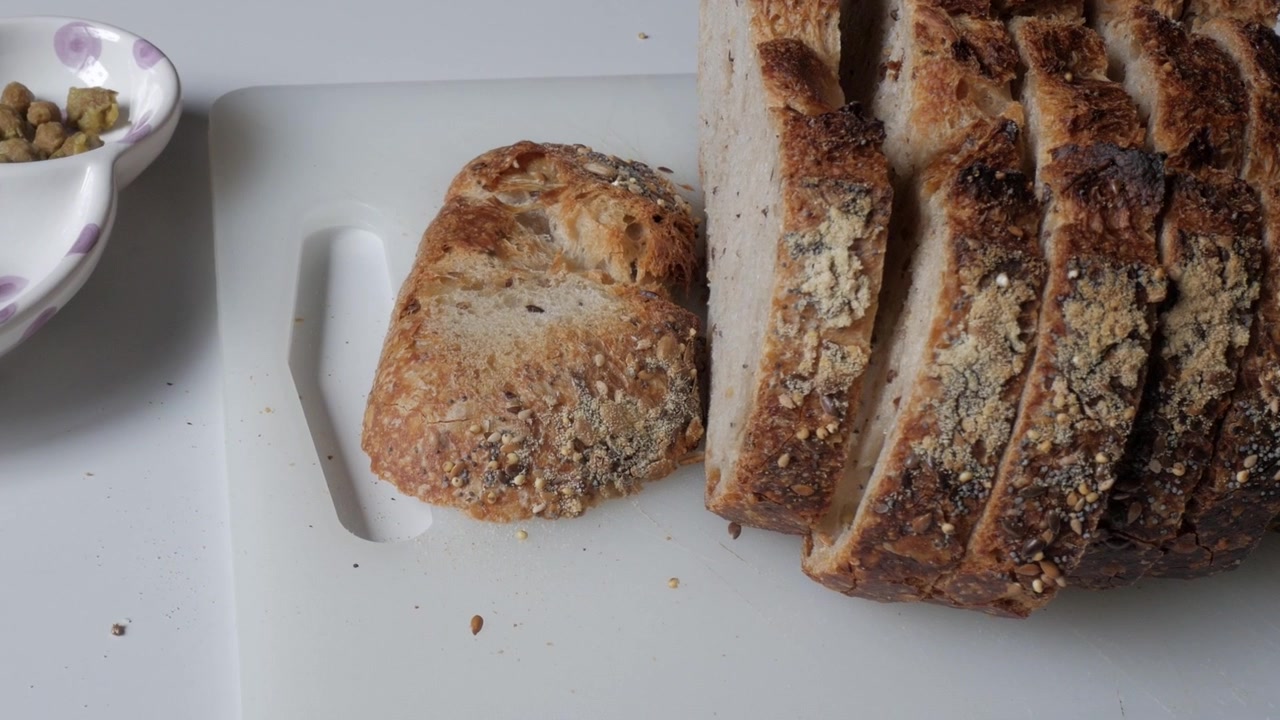 Aufgeschnittenes Brot mit Oliven auf einem Schneidebrett, rustikal und einladend