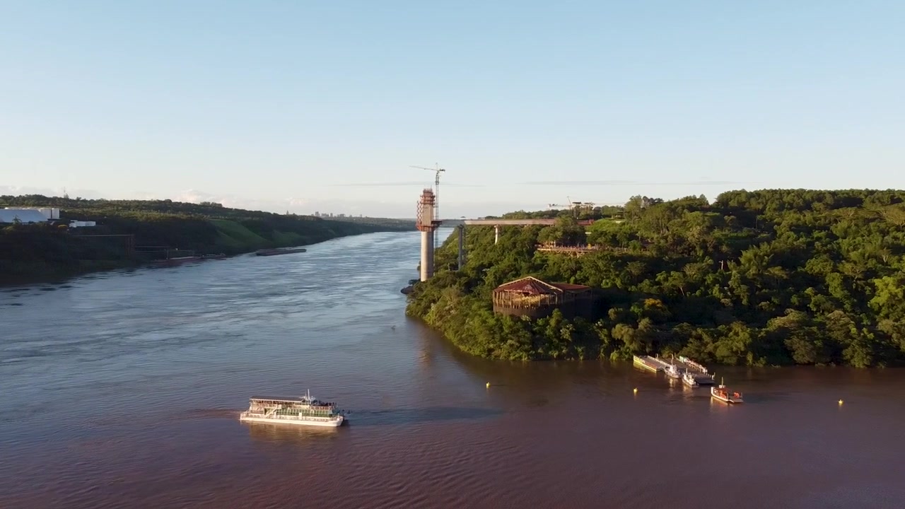 Ripresa aerea panoramica del fiume Iguazu in Argentina durante un tramonto dorato con barca turistica - Confine tra Brasile, Paraguay e Argentina