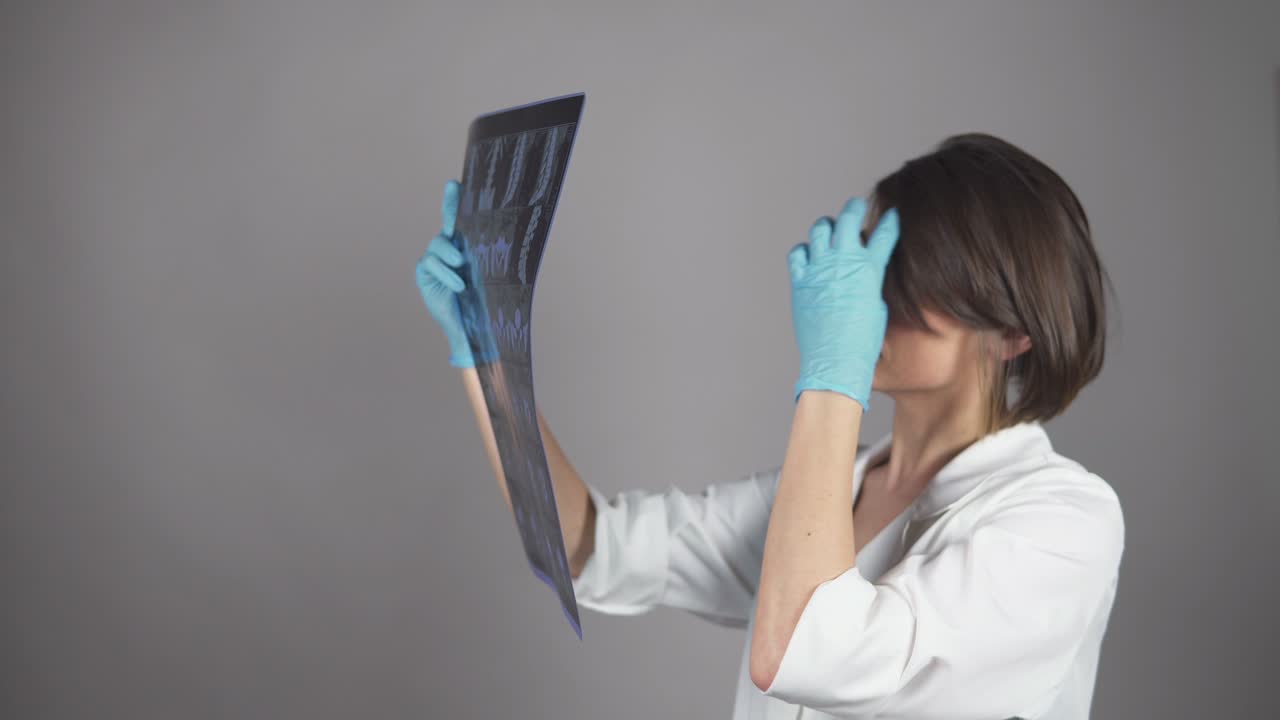 joven enfermera revisando rayos x aislados en fondo blanco. concepto de atención médica. filmado en 4k