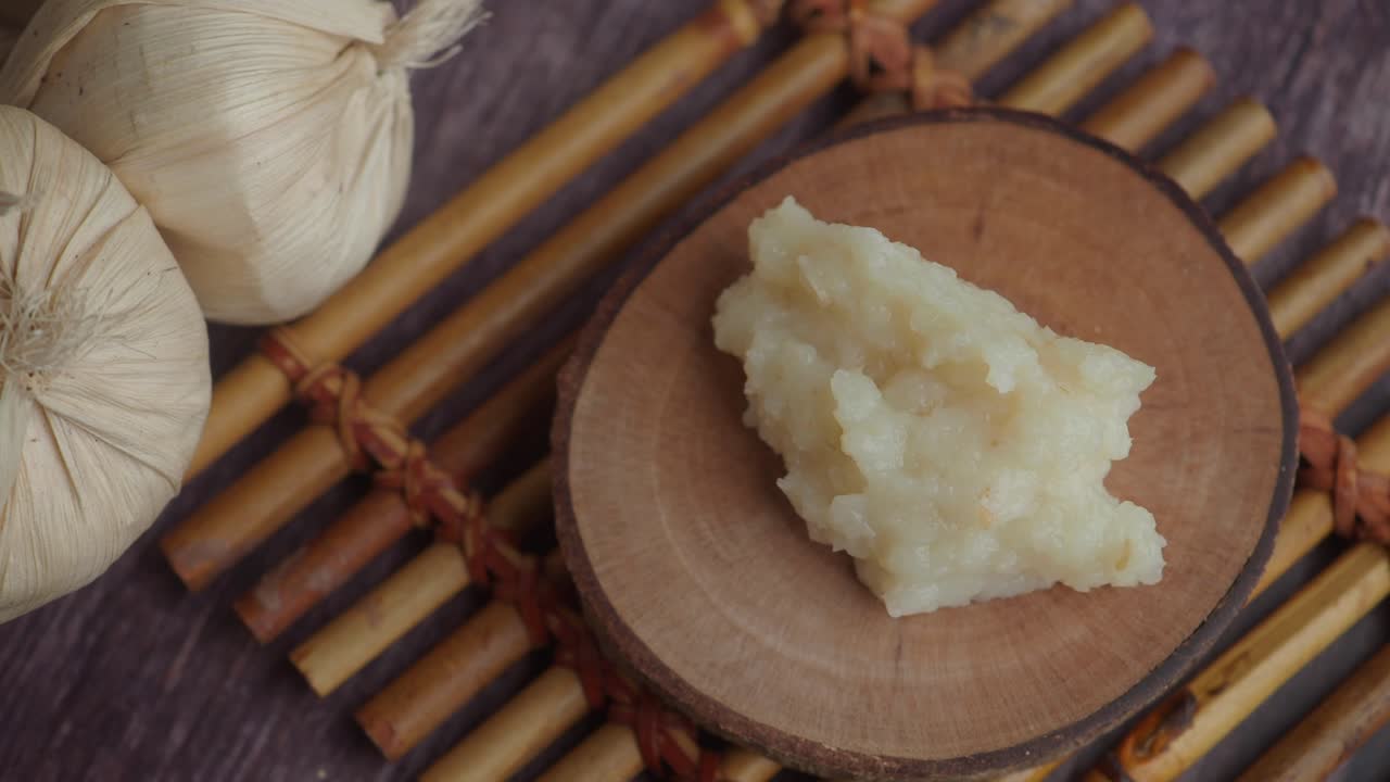 Aglio fresco tritato su un piatto di legno con teste d'aglio.