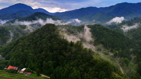 Dawn hills in the mountains. Rolling hills blanketed in mist greet the morning light above a winding road and quaint houses in the mountains