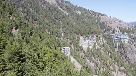 Vista-Aérea-De-Modernos-Edificios-De-Gran-Altura-Ubicados-En-Un-Profundo-Bosque-De-Pinos-En-La-Ladera-De-Una-Montaña