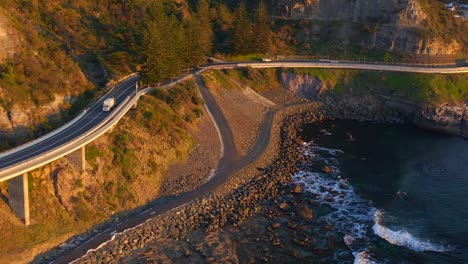 cars drive by steel bridge of sea cliff in ilawarra coast and new south wales australia - aerial shot