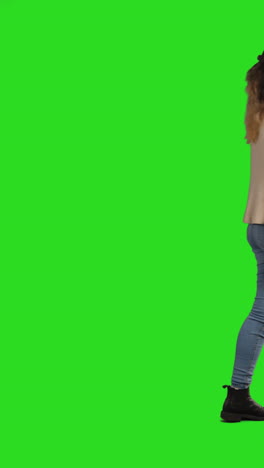 vertical video full length studio portrait of female teacher or businesswoman walking across frame carrying folder against green screen