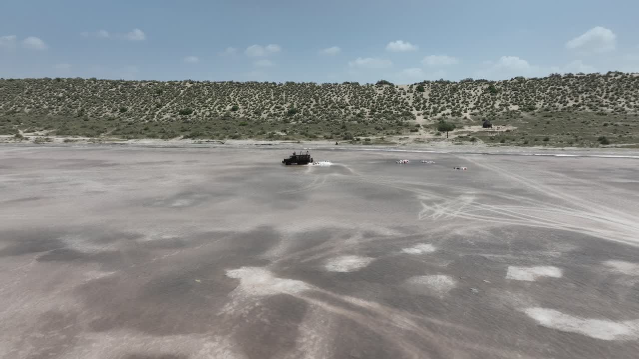 drone aéreo hacia adelante disparo en movimiento volando sobre los trabajadores que recogen sal de un lago salado en sanghar, sindh, pakistán en un día soleado