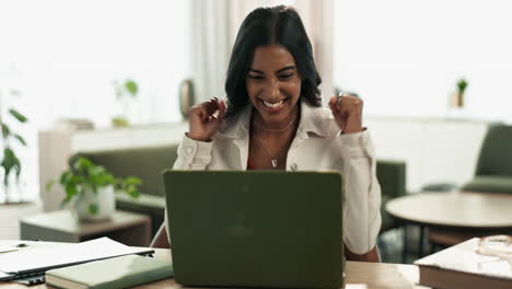 Woman celebrating success while working on laptop at home