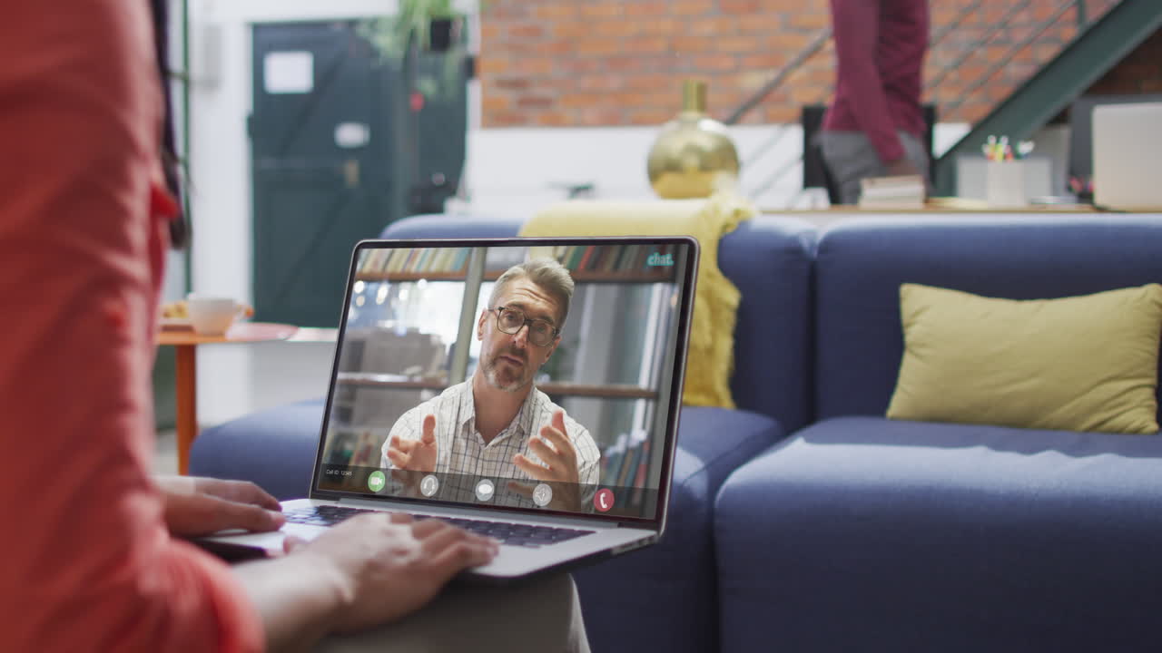 Biracial businesswoman using laptop for video call with caucasian business colleague