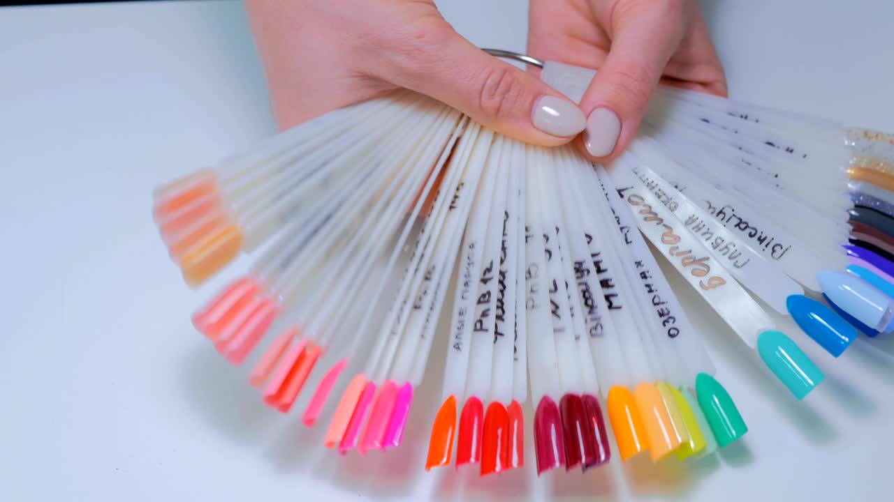 el técnico de uñas muestra la paleta de colores de los servicios de uñas en el salón de belleza.