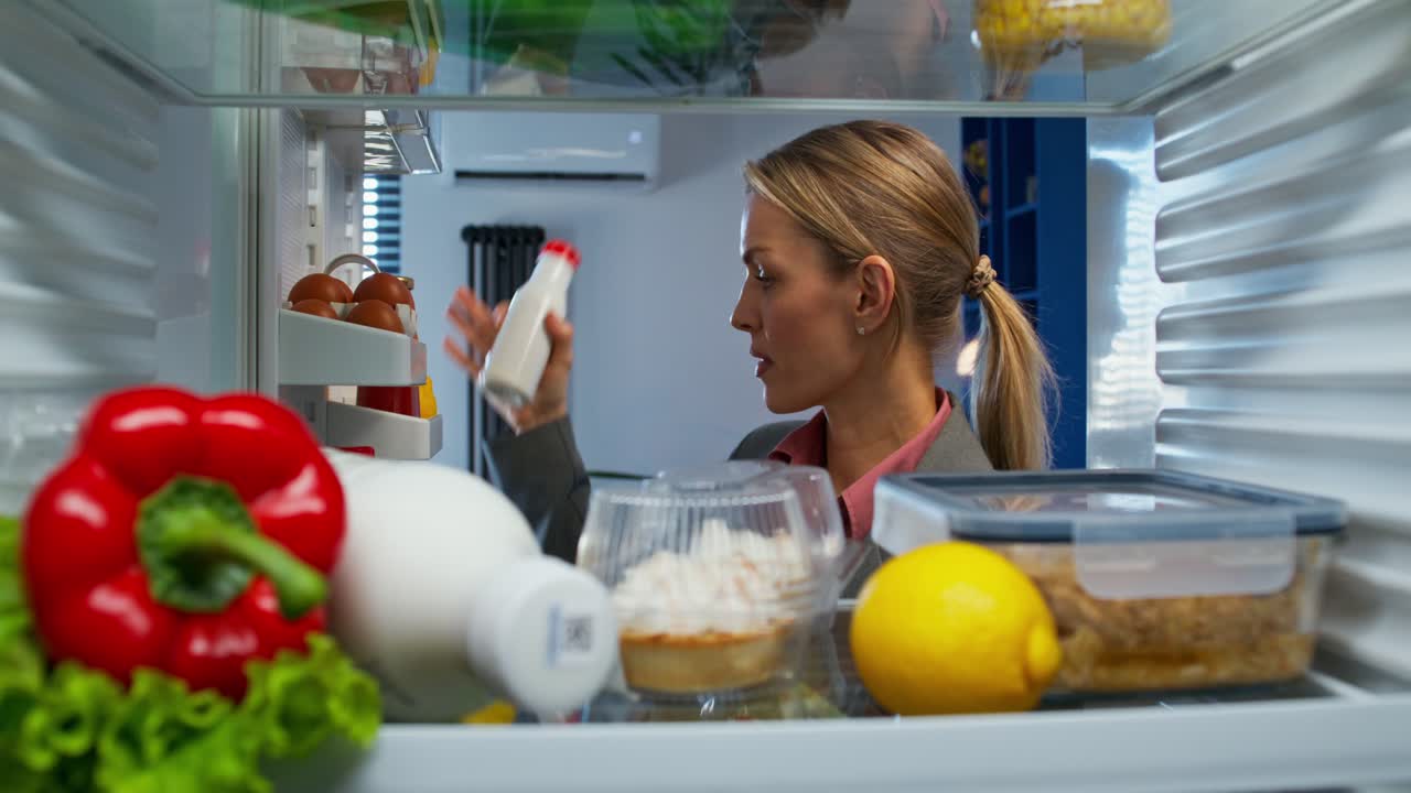 mujer comprobando y organizando comida en el refrigerador