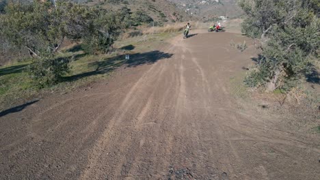 toma aérea de un dron estático de una pista de motocross cerca de málaga en españa con pilotos de motocross conduciendo alrededor de una curva hacia la cámara creando una nube de polvo