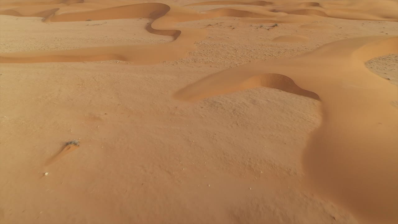 Patterns and textures of wind-swept sand dunes in El Agunia desert, Morocco, Africa. Aerial drone low flight, tilt-up reveal, copy space