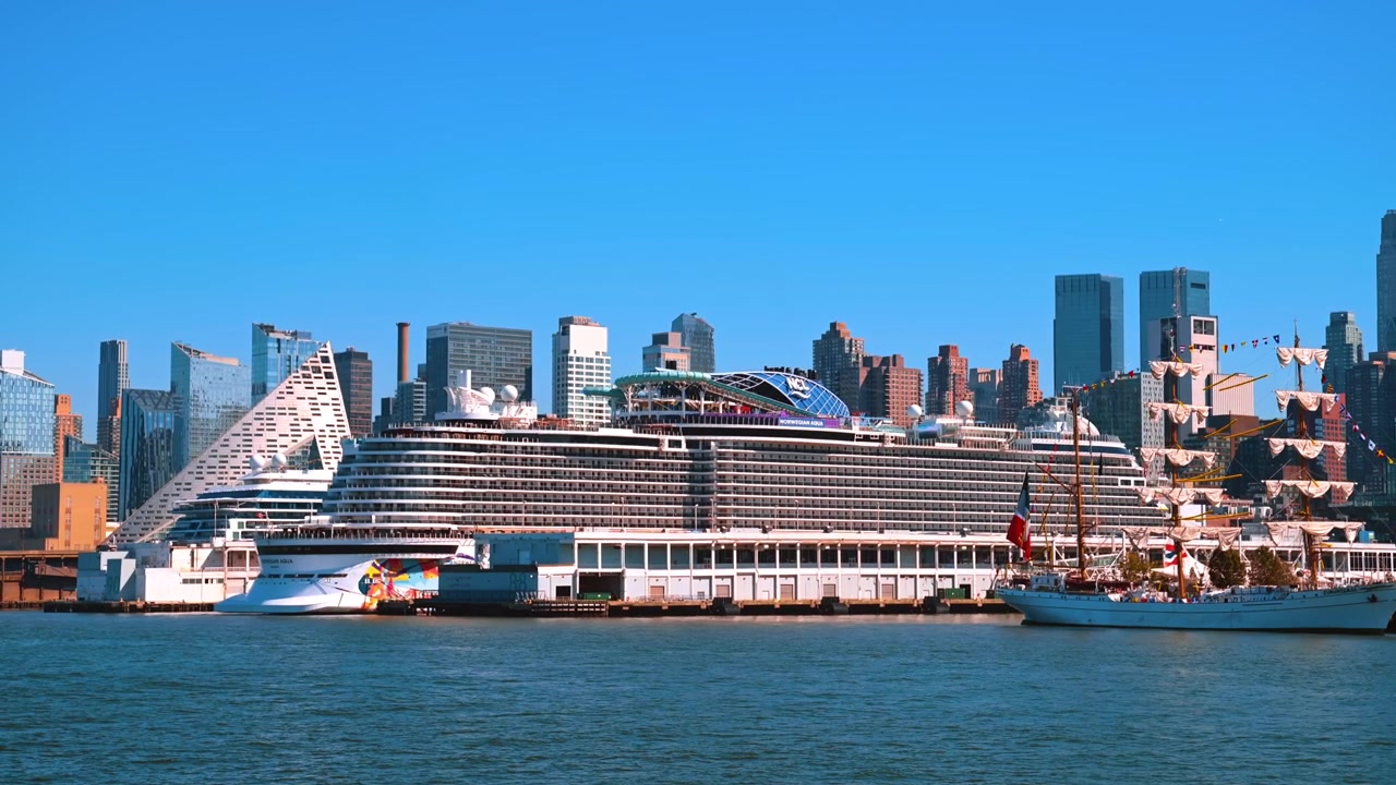 New York, USA, 4. maj 2026: Stort sejlskib passerer Norwegian Aqua langs Midtown Manhattans havnefront. Et sejlskoleskib med rullet sejl bevæger sig på Hudson River foran et dokket passagerskib og byens skyline.