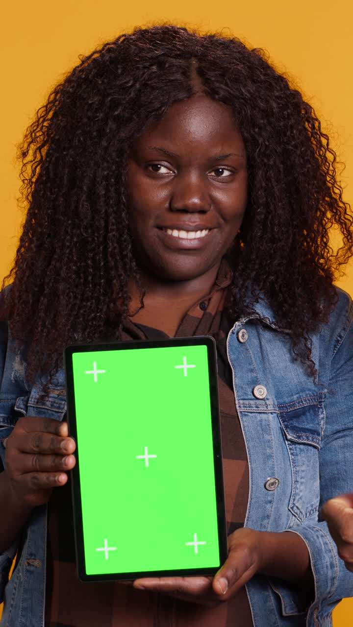 Donna afroamericana sorridente che tiene in mano un tablet con green screen