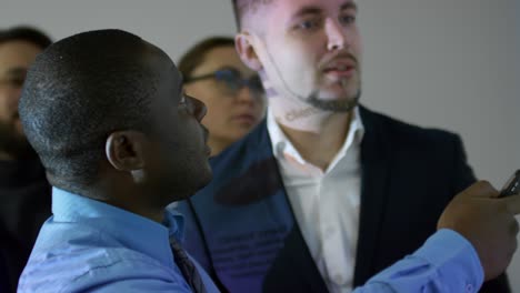 hombre de negocios africano mostrando una presentación a sus colegas en una oficina oscura