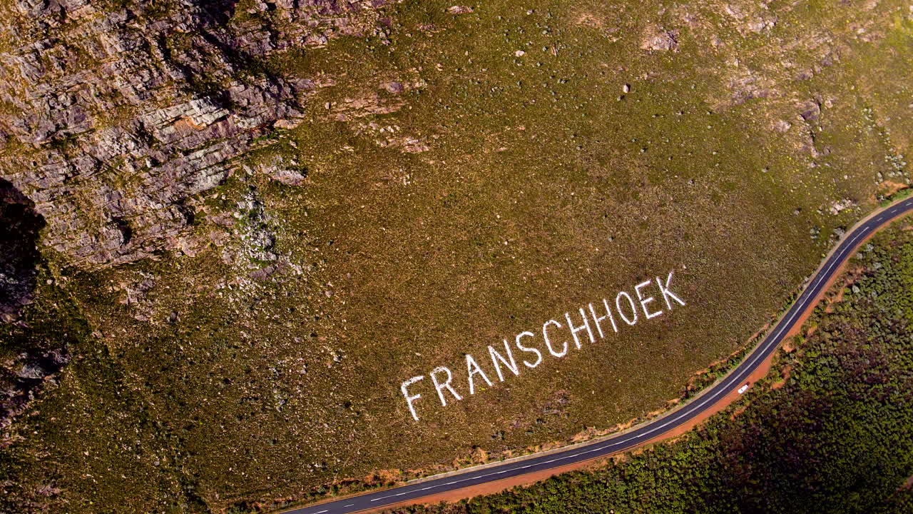 Rotating aerial shot over Franschhoek place name on mountainside of pass