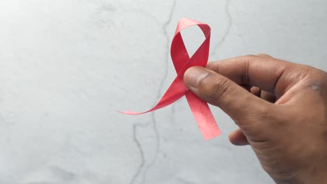 hand holding a red ribbon