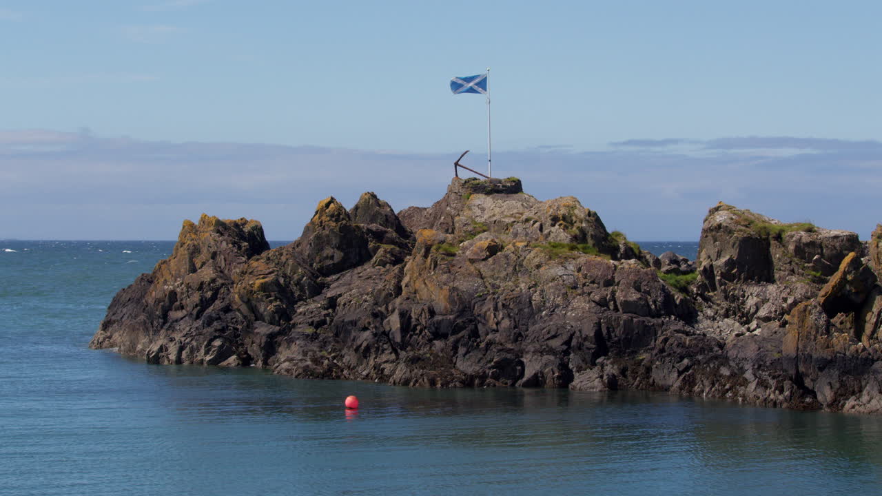 extra wide shot of the Scottish saltire flag on a rocky outcrop at portPatrick harbour