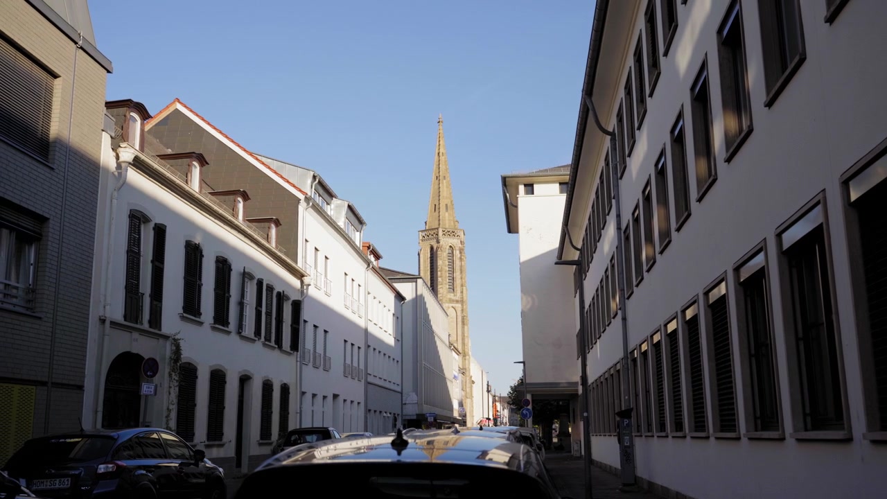 Vista lungo una strada di una città europea verso una storica torre campanaria nel centro di Saarlouis, Germania.