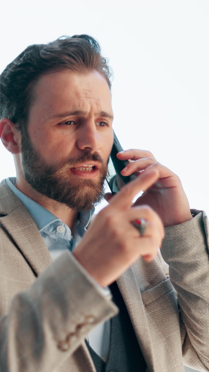 Serious Businessman Talking on Smartphone and Gesturing Outdoors