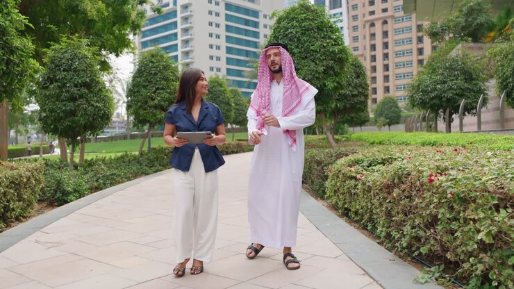 Professionisti d'affari asiatici e arabi sorridenti utilizzano un tablet durante una consultazione all'aperto.