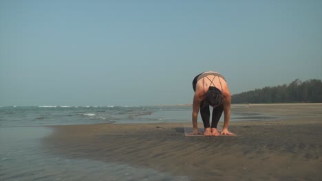 athletic person jumping to plank while doing yoga along the beach in the sunshine before ending in upward facing dog position