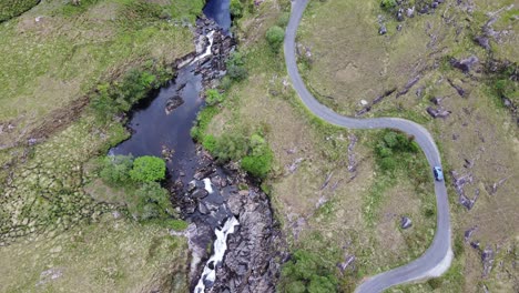 road curve and river curve next to it, while car slowly passes by, a direct view from above