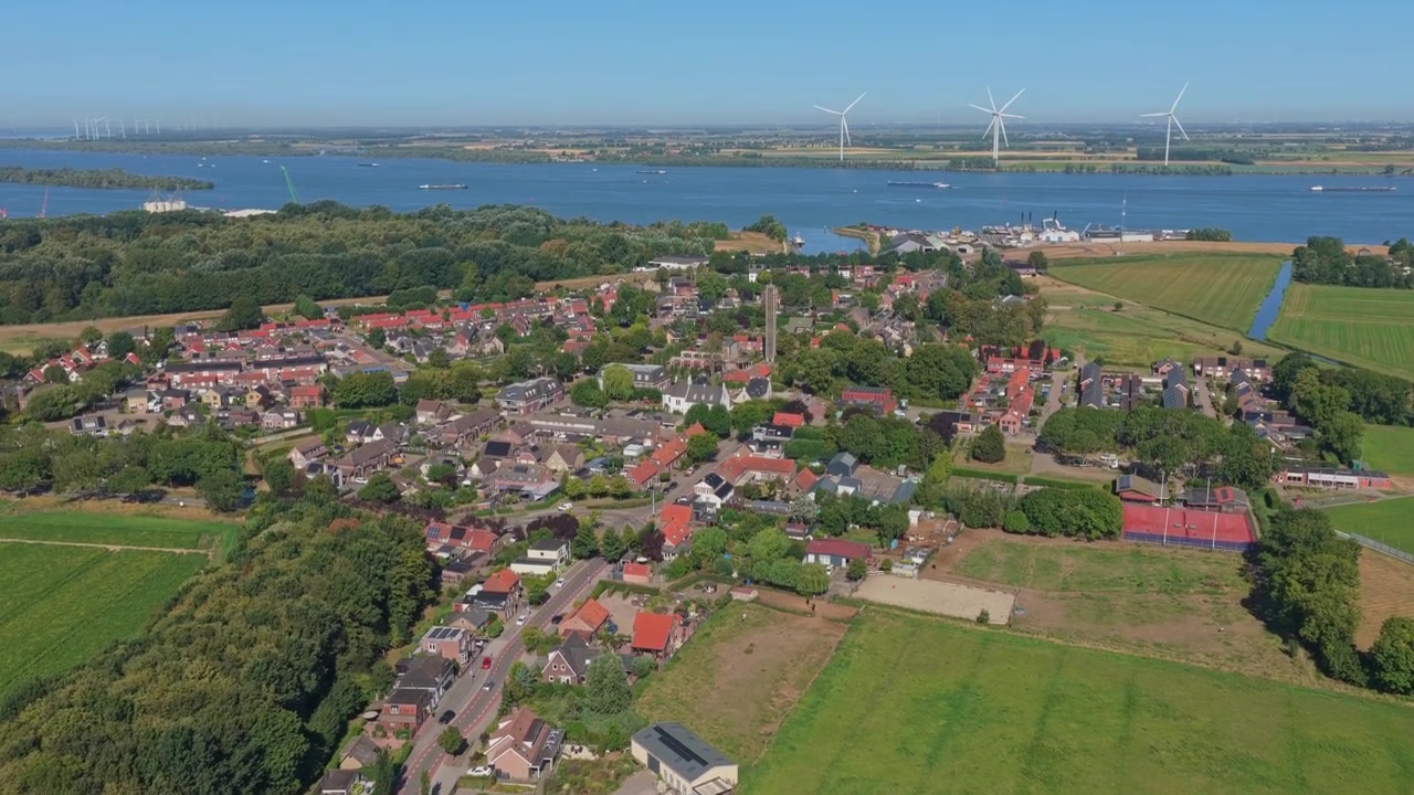 Prospettiva da drone che sorvola la rigogliosa campagna olandese, rivelando l'incantevole villaggio di Moerdijk immerso tra campi verdi e acqua