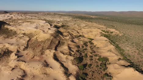 Aerial-view-of-massive-sand-dunes-among-rocky-mountains-in-the-arid-region-of-the-Northern-Cape,-South-Africa