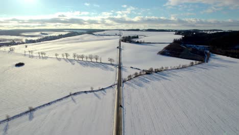 Vista-Aérea-De-Una-Carretera-Que-Conduce-Al-Horizonte-Con-Camiones-En-Movimiento-En-Un-Paisaje-Nevado