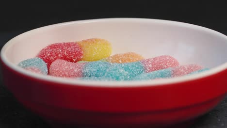 colorful gummy worms in a red bowl