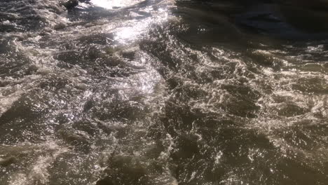 Outdoors view of natural fast whitewater river flowing on a sunny day
