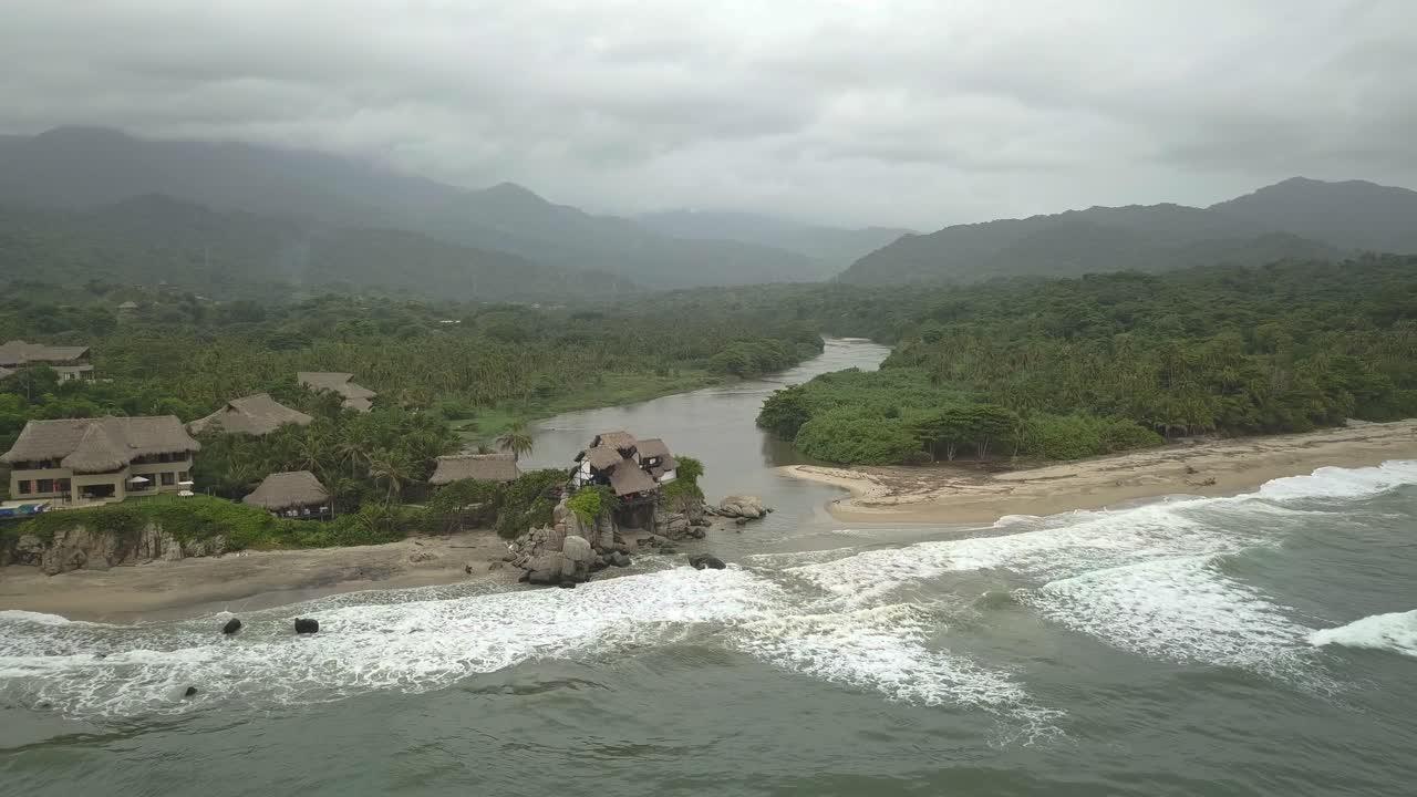 hermosa toma de un dron de una playa y un río de la selva en el parque nacional tayrona en colombia con montañas en el fondo