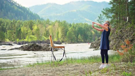 woman painting outdoors by a river
