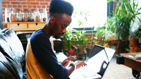 Man-using-laptop-and-smart-watch-in-the-living-room