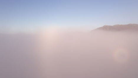 disparo de drones que se eleva a través de espesas nubes para revelar montañas y un valle lleno de nubes